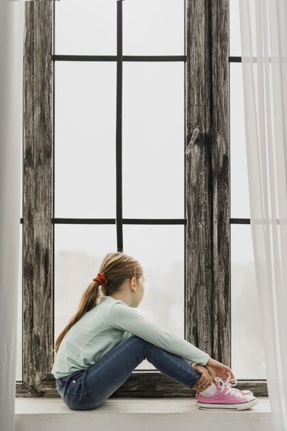 流行病坐在窗台上的小女孩室内家安全