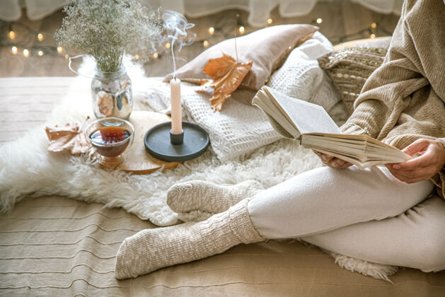 舒适惬意的秋天在家 一个女人拿着一本书在休息一种惬意的生活方式身体部位在作曲袜子女人温暖