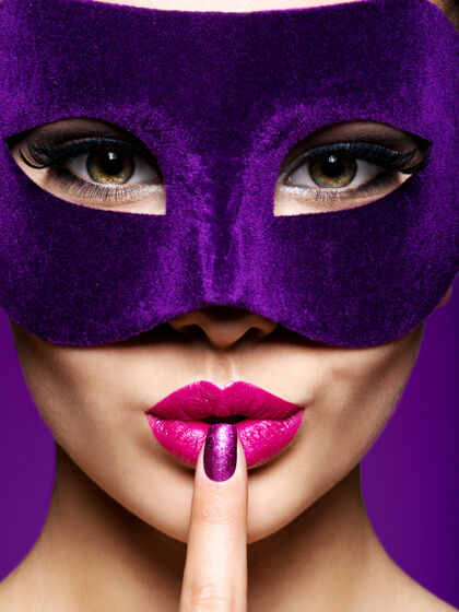 迷人一个戴着紫罗兰色指甲和戏院面具的美丽女人的肖像紫色背景穿着高加索