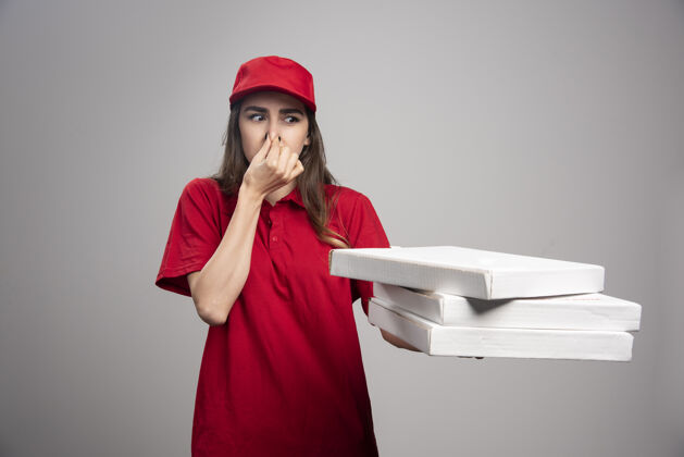 香味送货员在搬运比萨饼盒时紧紧地捏着鼻子披萨服务年轻人