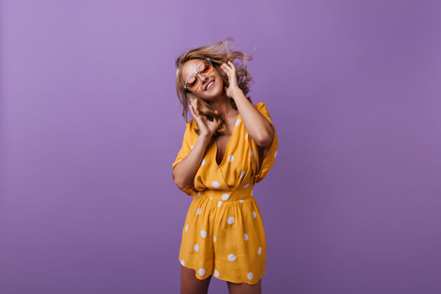 有趣迷人的欢笑女子在跳舞温文尔雅的棕褐色女孩穿着橙色的衣服在紫色上微笑爱享受放松