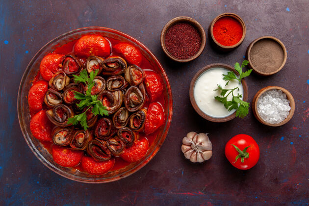 美味俯瞰煮熟的蔬菜餐美味的西红柿和茄子与调味料酸奶油在黑暗的表面烹饪番茄胡椒