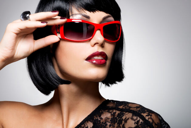 优雅一个漂亮的黑发女人的时尚肖像 带着红色太阳镜的发型性感直化妆