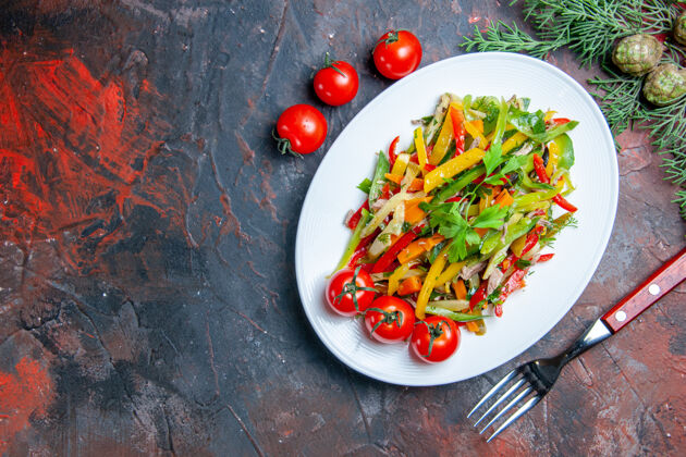 辣椒俯视蔬菜沙拉椭圆形盘子樱桃西红柿叉子暗红色桌子复制空间蔬菜蔬菜沙拉番茄