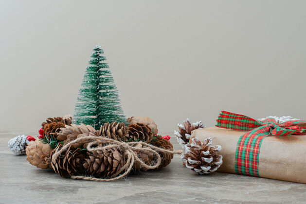 玩具圣诞礼盒 松果和花圈放在大理石桌上装饰品圣诞丝带