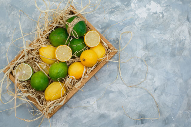 健康一些酸橙和柠檬 用木箱放在灰色和蓝色的大理石表面饮食新鲜配料