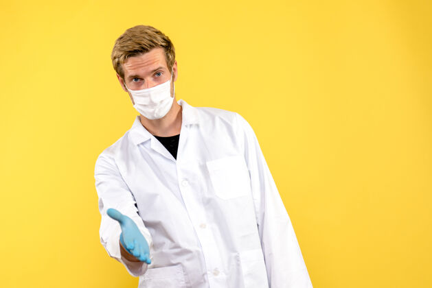 男性医生正面图黄色背景上男医生问候健康冠状病毒大流行外观成人实验室外套