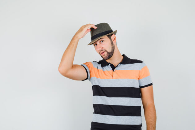 帽子一个穿着t恤的年轻人举起帽子 看上去很优雅提升现代成功