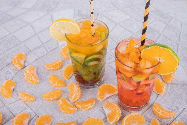 新鲜两杯果汁和水果片放在大理石表面提神水果饮料