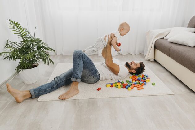 团结高角度的爸爸和宝宝在地板上玩父亲家庭男人