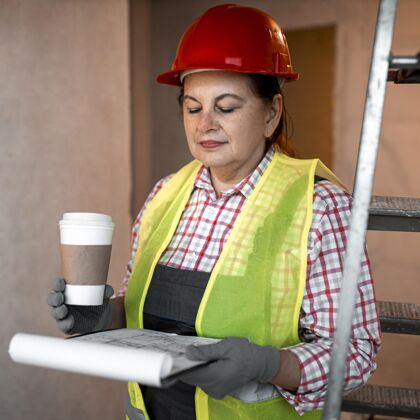工作女建筑工人正拿着咖啡和平面图技能专业知识建筑工人