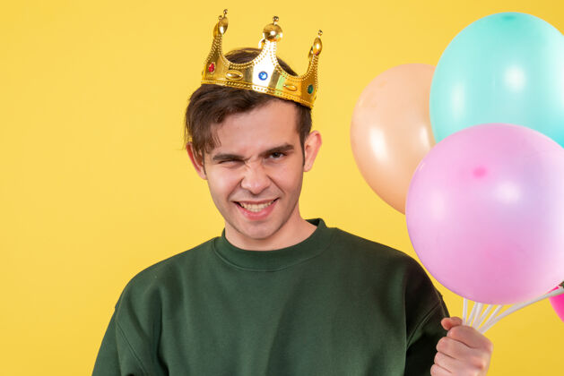 帅哥年轻人正面图戴皇冠的帅哥拿着黄色的气球快乐工艺年轻