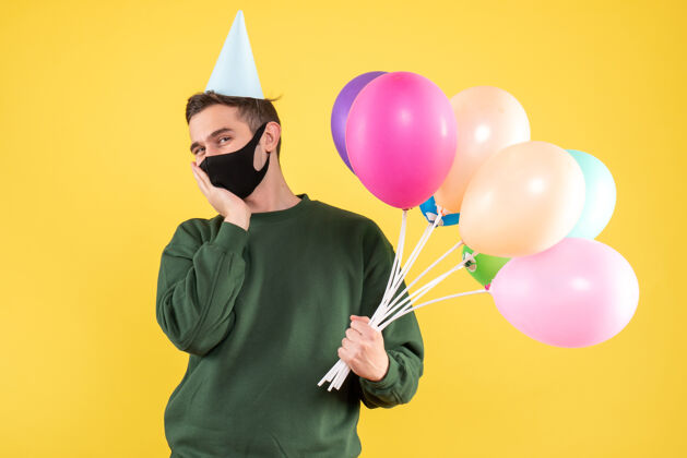 庆祝正面图快乐的年轻人戴着派对帽 站在黄色的气球上乐趣庆祝聚会