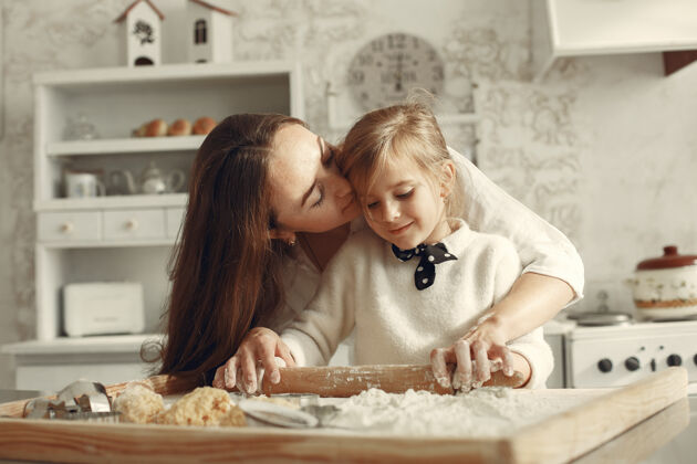 微笑一家人在厨房里漂亮的妈妈带着小女儿面包房长家