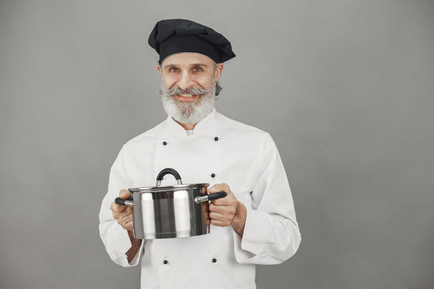 潘高级男子与金属锅厨师在一个黑色的帽子专业的方法来处理业务烹饪人自助餐