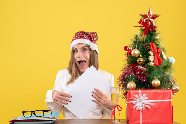 前面前视图女医生坐在圣诞礼物持有黄色背景文件文件女性快乐