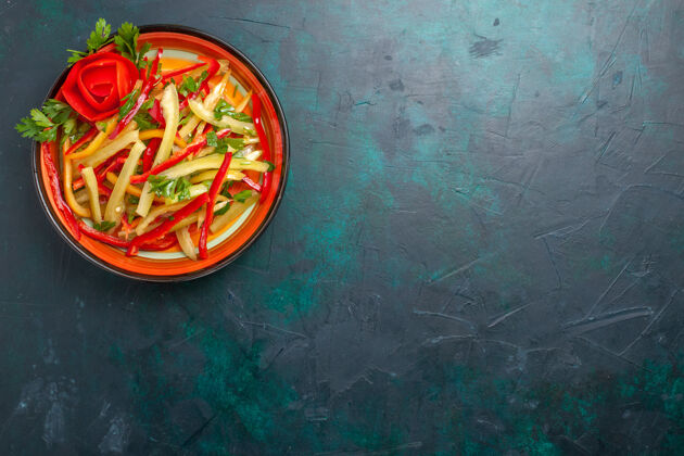 深蓝色顶视图切片甜椒不同颜色的蔬菜沙拉在深蓝色的背景板内盘子蔬菜胡椒粉