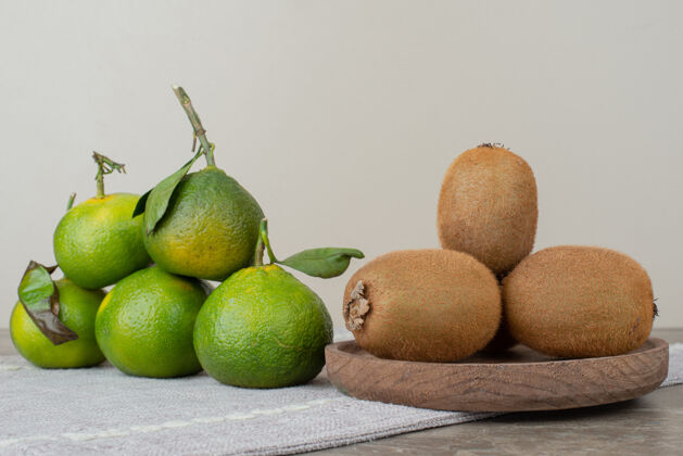 猕猴桃在灰色桌布上放上奇异果和新鲜橘子盘子成熟有机