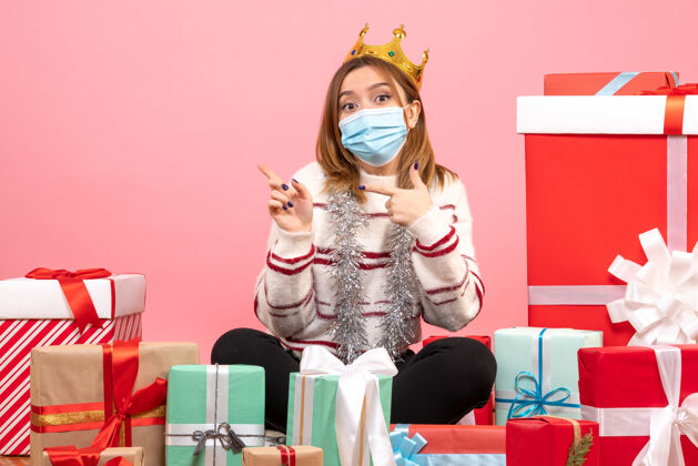 女性正面图：年轻女性戴着无菌面具围坐在圣诞礼物旁面具节日礼物
