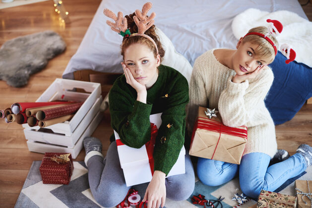 礼物两个无聊的女孩在为圣诞节准备圣诞礼物装饰悲伤包
