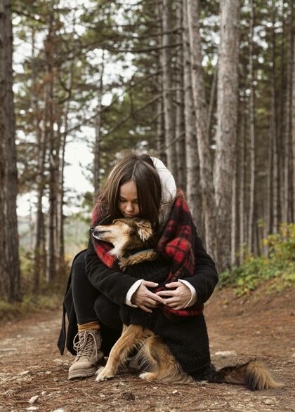 女人在森林里拥抱她的狗的年轻女人放松森林狗