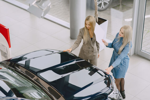美女汽车沙龙里的女士买车的女士穿着蓝色裙子的优雅女士经理帮助客户租车经销商汽车