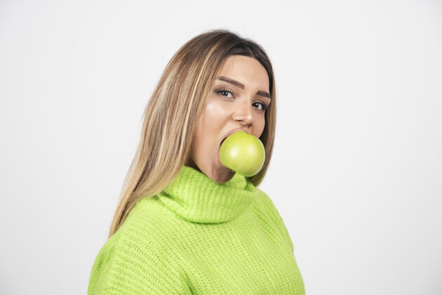 食欲穿着绿色t恤的年轻女子正在吃苹果吃膳食苹果