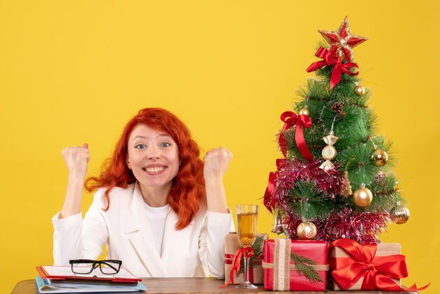 女医生前视图女医生坐在桌子后面 黄色的圣诞礼物女地板庆祝