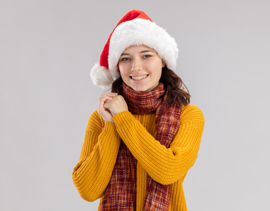 手戴着圣诞帽 脖子上围着围巾 面带微笑的年轻斯拉夫女孩双手合十 神气活现复制斯拉夫围巾