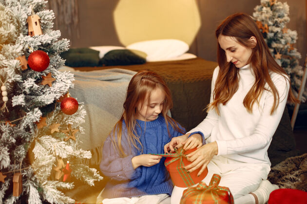 家人们在为圣诞节做准备母亲在和女儿玩耍一家人在节日的房间里休息孩子穿着蓝色毛衣孩子女儿装饰