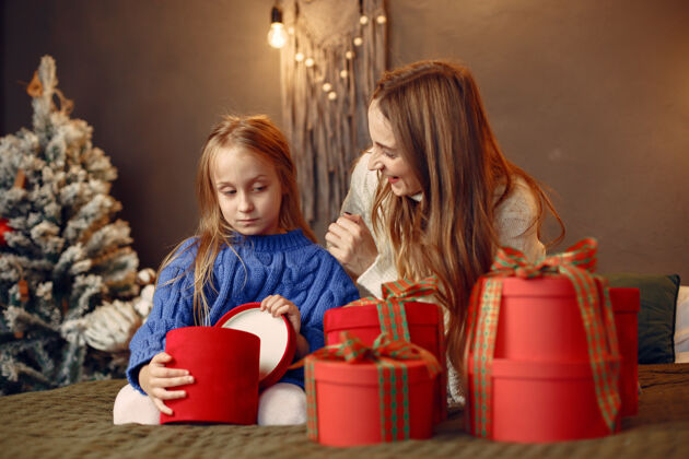传统人们在为圣诞节做准备母亲在和女儿玩耍一家人在节日的房间里休息孩子穿着蓝色毛衣给庆祝女性