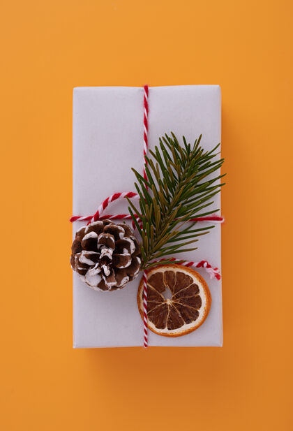 礼物用红丝带 冷杉树枝 松果和干橘子片装饰的白色礼盒树枝盒子装饰