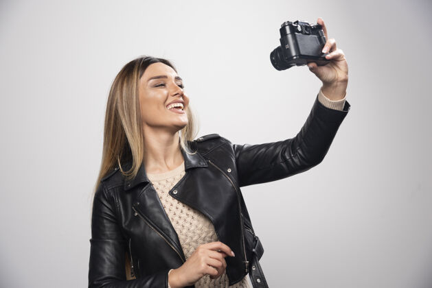 女人一位身穿黑色皮夹克的年轻女士 以积极微笑的态度 用相机拍照年轻人人类员工