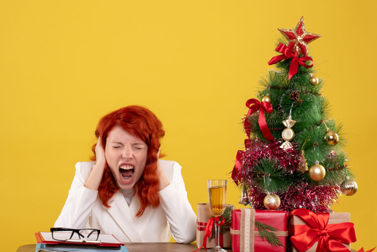 坐着女工人坐在桌子后面 拿着圣诞树和黄色的礼物成人黄色圣诞节