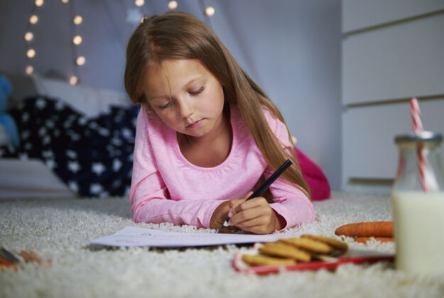 绘画活动躺在前面写信的女孩圣诞节时间家庭室内前视图