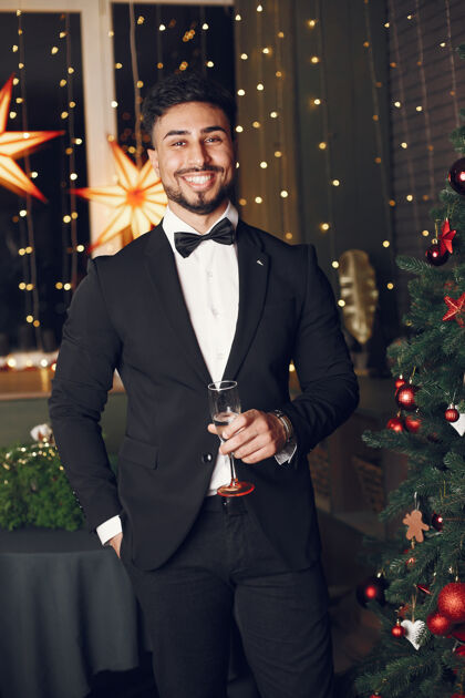 男人圣诞树旁的帅哥穿着黑色西装的绅士夜晚人黄金