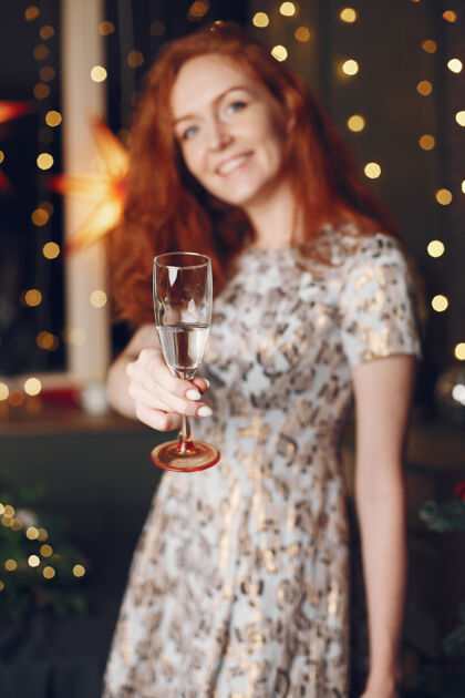 庆祝圣诞树旁的优雅女士家里拿着香槟的女士女人人年