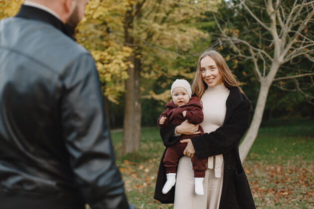 成年人一家人在秋天的公园里男人穿着黑色夹克可爱的小女孩和父母衣服父母母亲