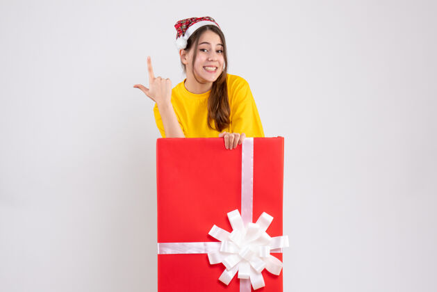 快乐女孩戴着圣诞帽的快乐女孩站在白色圣诞礼物后面购物人快乐