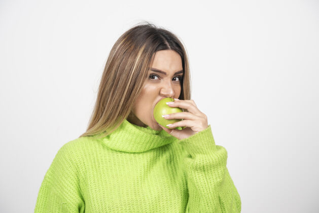 美丽穿着绿色t恤的年轻女子正在吃苹果健康食物饮食