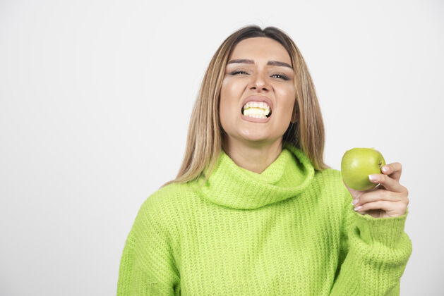 美丽穿着绿色t恤的年轻女子正在吃苹果营养女性表情