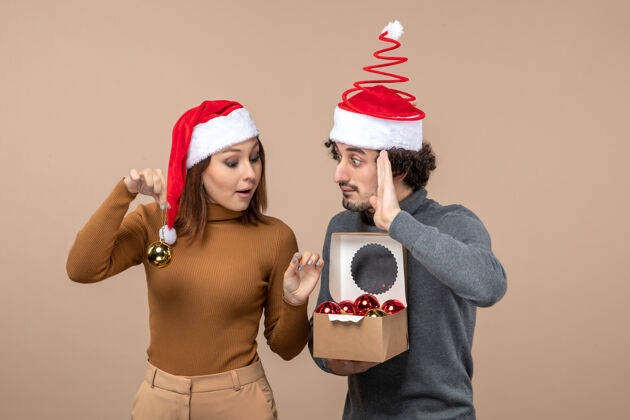男人喜庆的心情与兴奋有趣的酷夫妇戴着红色圣诞老人帽的灰色镜头圣诞老人镜头圣诞