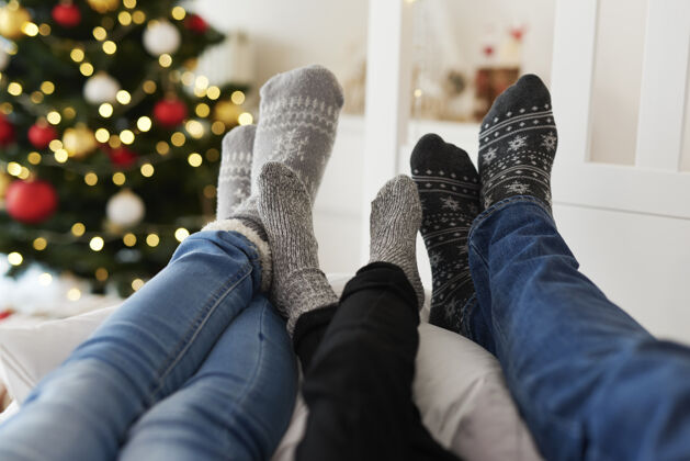 圣诞穿着暖和袜子的一家人的腿的特写镜头温暖室内温度