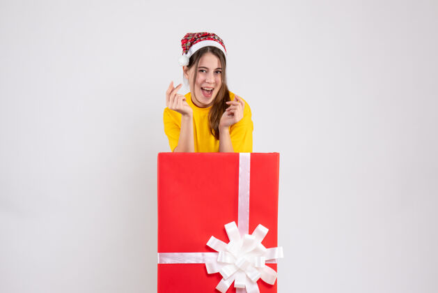 女孩快乐可爱的女孩 戴着圣诞帽站在白色圣诞礼物后面礼物礼物丝带