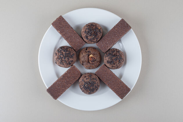 美味巧克力薄饼和巧克力饼干放在大理石背景的盘子里小吃美味甜食