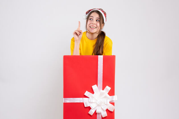 礼物圣诞快乐女孩戴着圣诞帽站在白色圣诞礼物后面销售大圣诞节