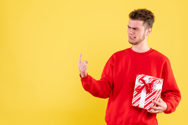 年轻正面图：穿着红色衬衫的年轻男性 带着圣诞礼物红色人情感