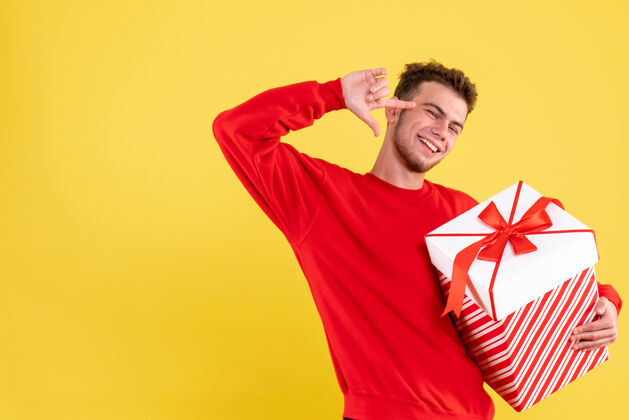 情感正面图：穿着红色衬衫的年轻男性 带着圣诞礼物年人颜色