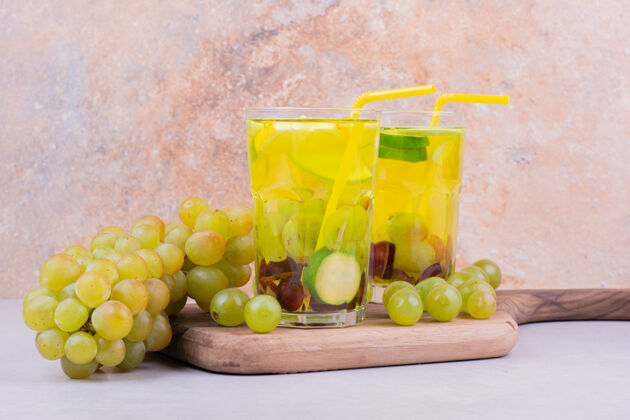 美味一束绿葡萄放在木板上 两杯果汁食物饮料品质