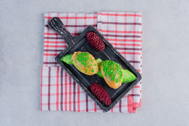 桌布美味的糕点和黑木板上的红松果糕点甜点烘焙